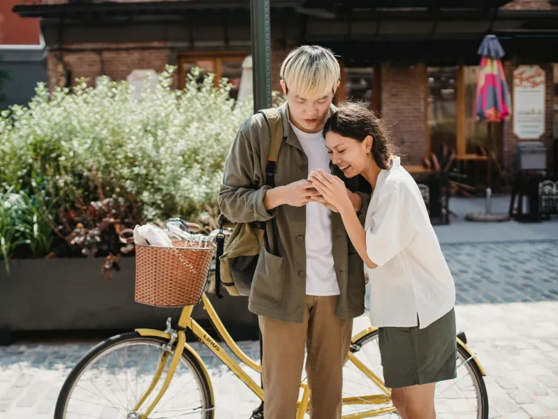 A happy couple sharing a moment of joy by their yellow bicycle in a charming outdoor setting, showcasing connection, love, and warmth.