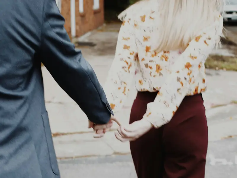 Two people holding hands while walking outdoors