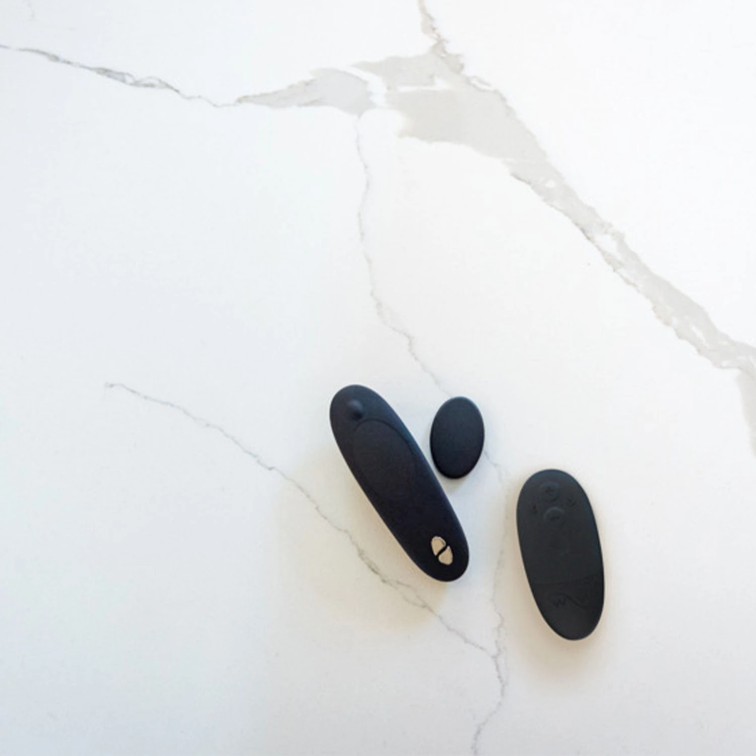 Black We-Vibe Moxie+ with remote and magnet clip on white marble surface