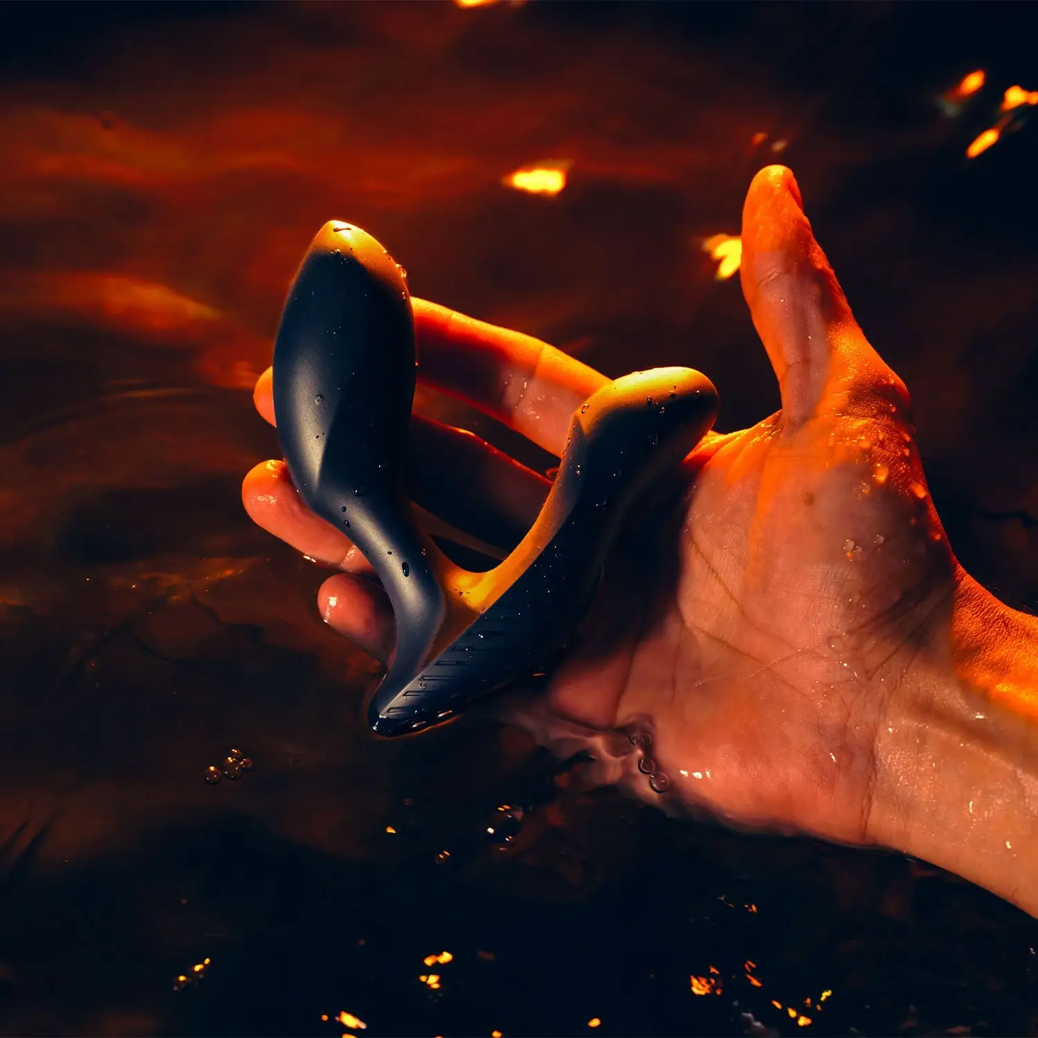 Hand holding Arcwave Perk black prostate vibrator in water