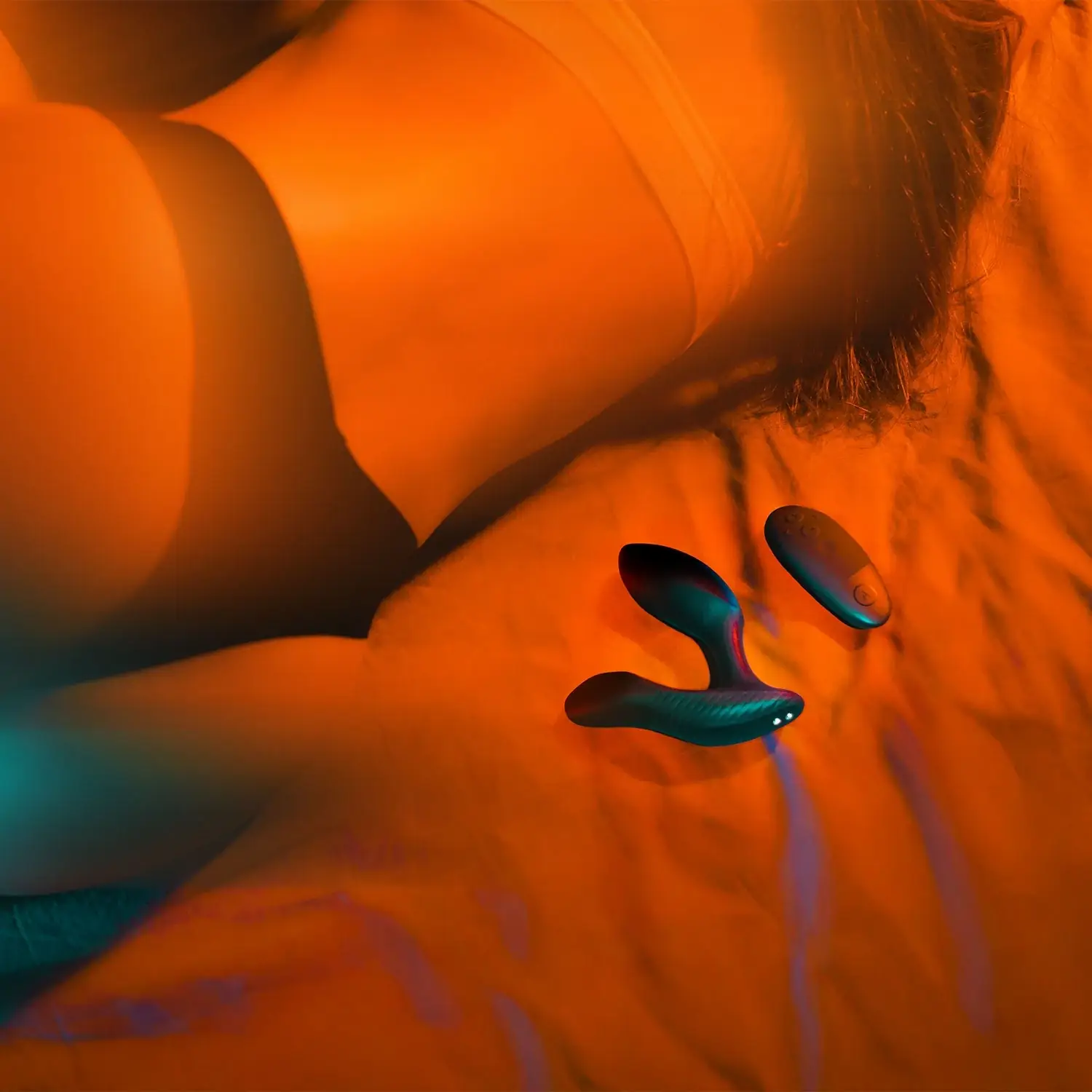 Arcwave Perk black prostate vibrator and remote placed on bed beside woman